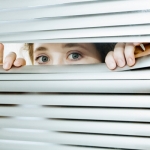 person peaking through blinds